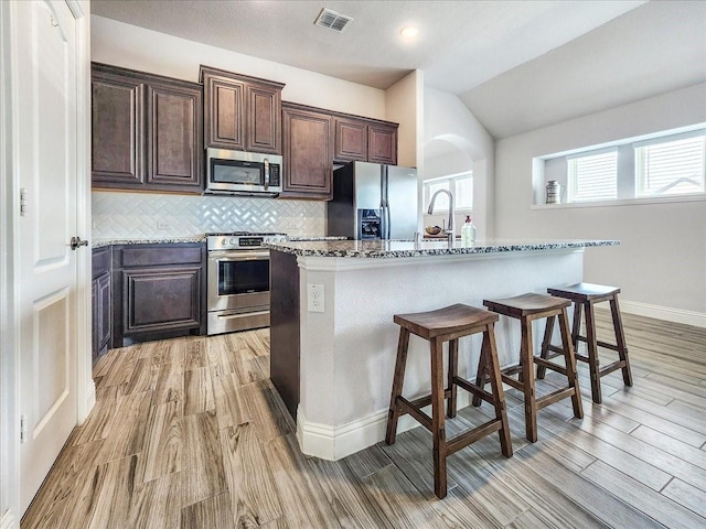 1152 Snowy Owl Dr, Alvarado, TX 76009 - kitchen with stainless steel appliances, a breakfast bar area, light wood-style flooring, decorative backsplash, and a sink