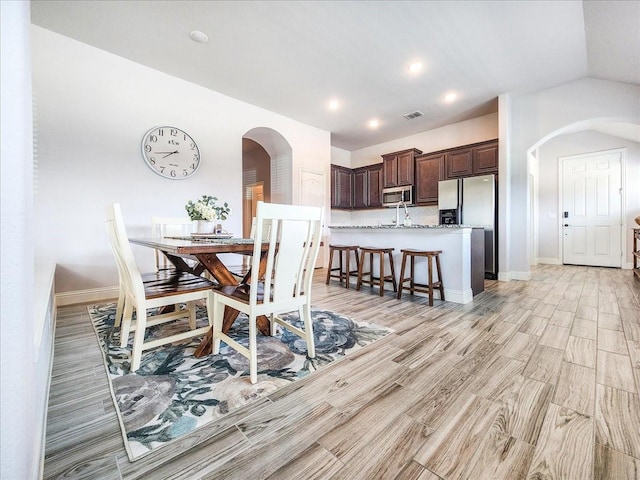 1152 Snowy Owl Dr, Alvarado, TX 76009 - dining area featuring arched walkways, light wood-style flooring, baseboards, recessed lighting, and lofted ceiling