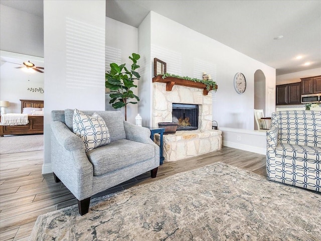 1152 Snowy Owl Dr, Alvarado, TX 76009 - living area featuring wood finished floors, a stone fireplace, a ceiling fan, and baseboards