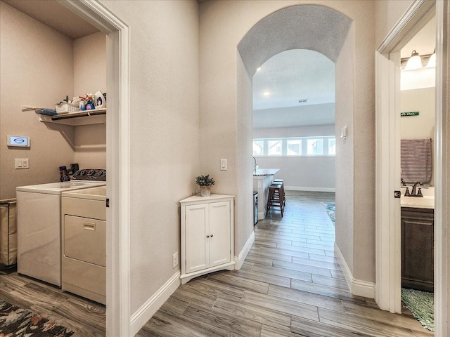 1152 Snowy Owl Dr, Alvarado, TX 76009 - hallway featuring washer and dryer, arched walkways, a sink, wood finished floors, and baseboards