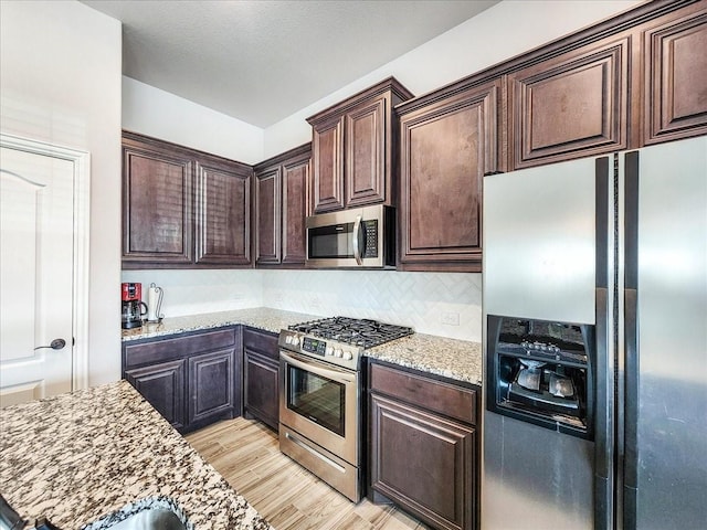 1152 Snowy Owl Dr, Alvarado, TX 76009 - kitchen featuring stainless steel appliances, dark brown cabinets, light wood-type flooring, light stone counters, and tasteful backsplash