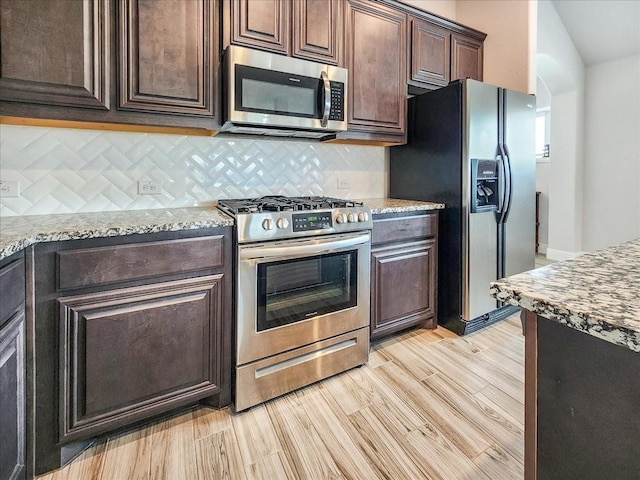 1152 Snowy Owl Dr, Alvarado, TX 76009 - kitchen with stainless steel appliances, decorative backsplash, dark brown cabinetry, and light stone countertops