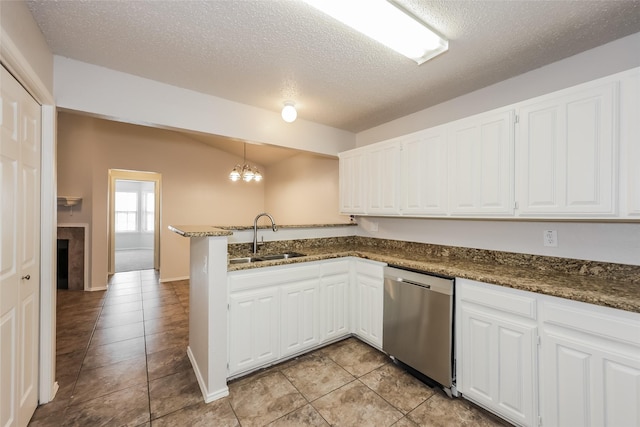 kitchen featuring dishwasher, a sink, a peninsula, white cabinetry, and a textured ceiling