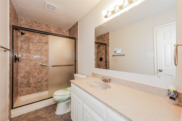 bathroom featuring a shower stall, toilet, a textured ceiling, and vanity