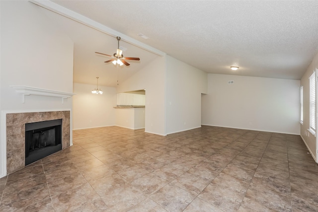 unfurnished living room featuring vaulted ceiling, a tiled fireplace, ceiling fan, a textured ceiling, and baseboards