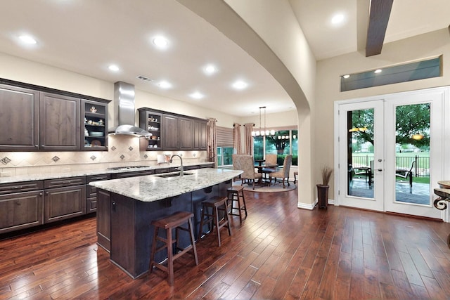 8916 Crestview Dr, Denton, TX 76207 - kitchen featuring wall chimney exhaust hood, arched walkways, a sink, a kitchen bar, and a kitchen island with sink