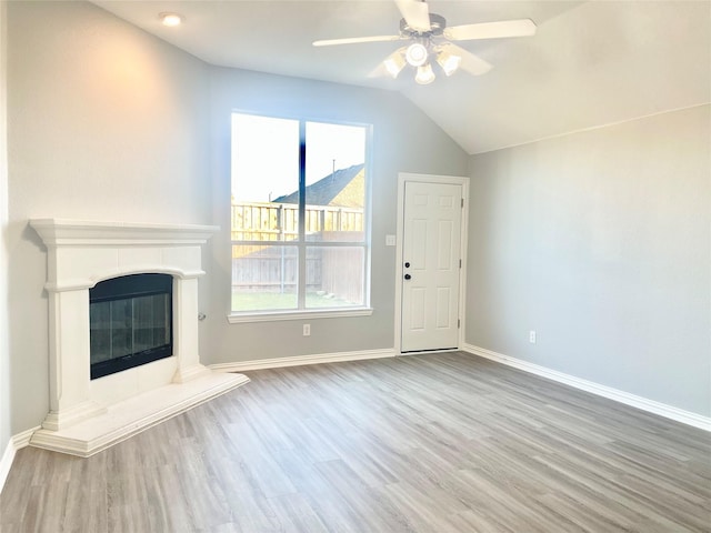 2632 Lake Ridge Dr, Little Elm, TX 75068 - unfurnished living room featuring wood finished floors, lofted ceiling, baseboards, ceiling fan, and a tiled fireplace