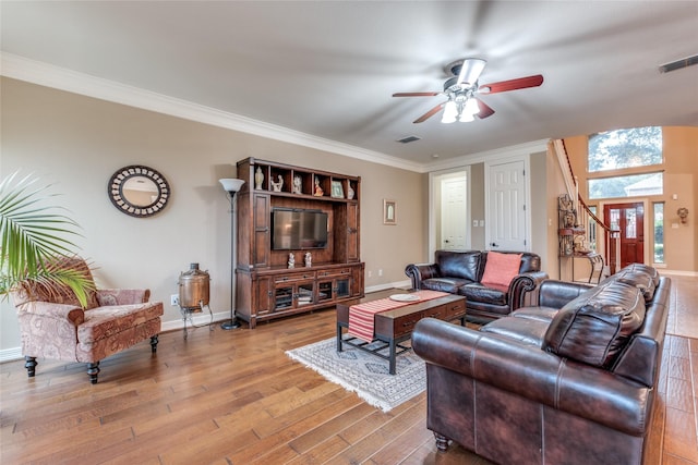 living area featuring a ceiling fan, wood finished floors, baseboards, and crown molding