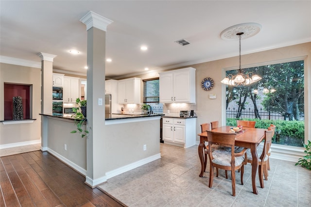 kitchen with dark countertops, ornamental molding, healthy amount of natural light, white cabinetry, and recessed lighting