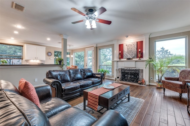 living area featuring crown molding, ceiling fan, wood finished floors, a fireplace, and a chandelier