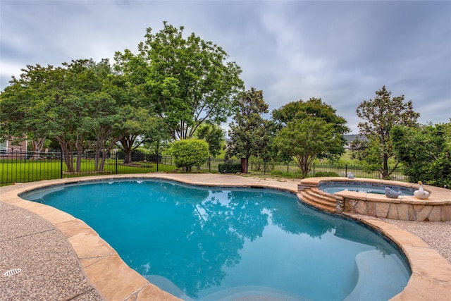 view of pool with a fenced backyard and a pool with connected hot tub