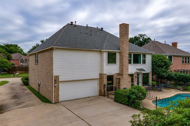 rear view of property featuring brick siding, fence, a patio, and a garage