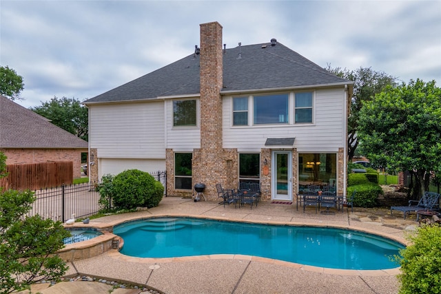 view of swimming pool featuring a patio, fence, and a pool with connected hot tub