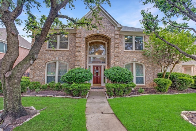 traditional home with brick siding and a front lawn
