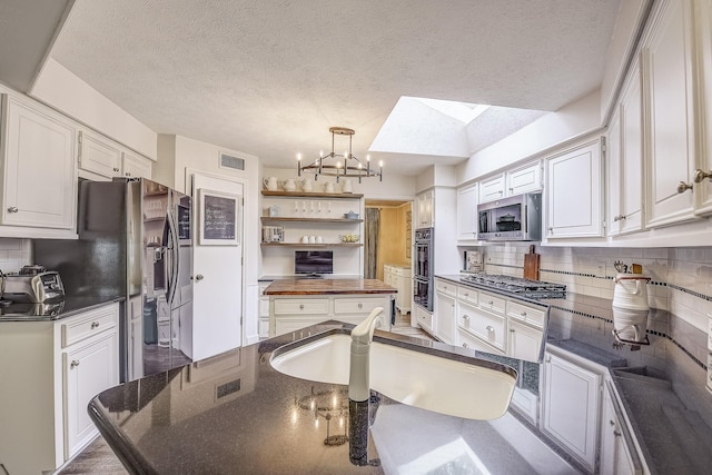 4020 Kerr Ct, Farmers Branch, TX 75244 - kitchen with appliances with stainless steel finishes, open shelves, a chandelier, a skylight, and tasteful backsplash