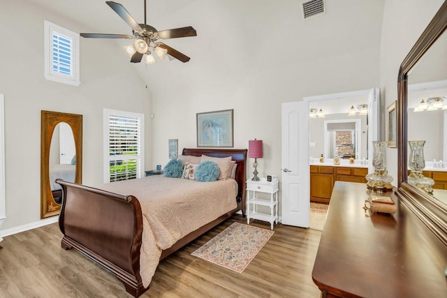 bedroom featuring high vaulted ceiling, light wood finished floors, ensuite bathroom, and a ceiling fan
