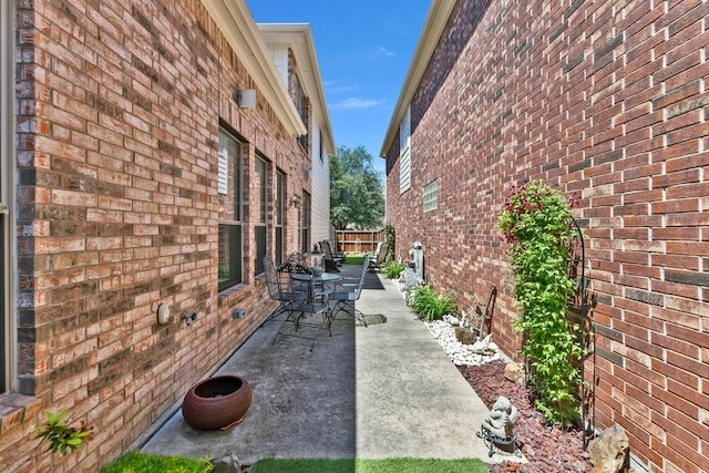 view of side of property with brick siding and a patio area
