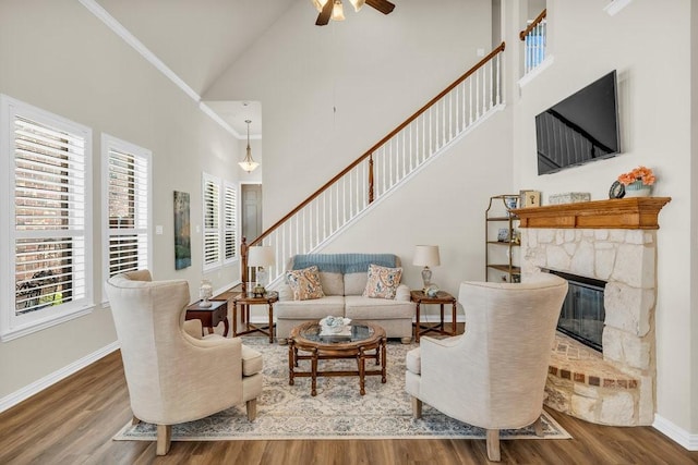 living area featuring wood finished floors, high vaulted ceiling, ceiling fan, and a fireplace