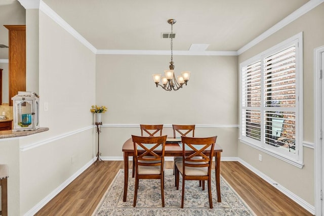 dining room featuring wood finished floors, a chandelier, crown molding, and baseboards