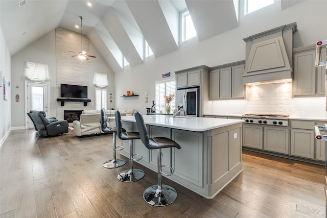 kitchen with gray cabinetry, appliances with stainless steel finishes, high vaulted ceiling, premium range hood, and light countertops