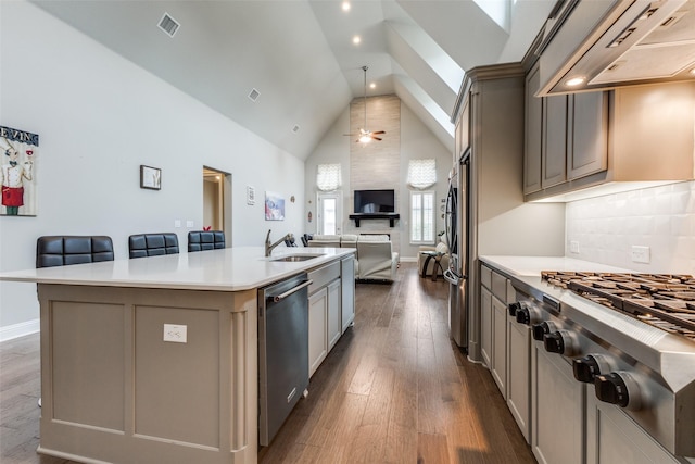 kitchen with stainless steel appliances, premium range hood, open floor plan, an island with sink, and high vaulted ceiling