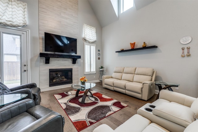 living area with wood finished floors, a high end fireplace, high vaulted ceiling, and baseboards