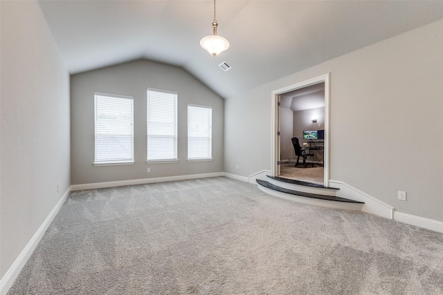 unfurnished living room featuring carpet flooring, vaulted ceiling, baseboards, and a desk
