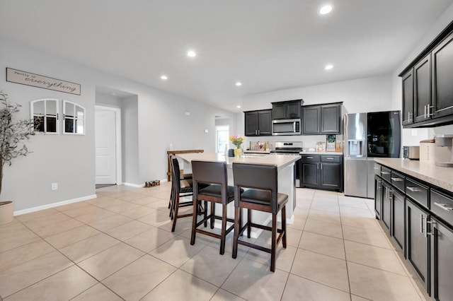 kitchen with stainless steel appliances, light tile patterned floors, light countertops, a kitchen island, and recessed lighting