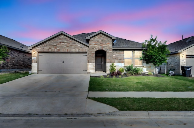 french country inspired facade featuring concrete driveway, a front yard, an attached garage, brick siding, and stone siding