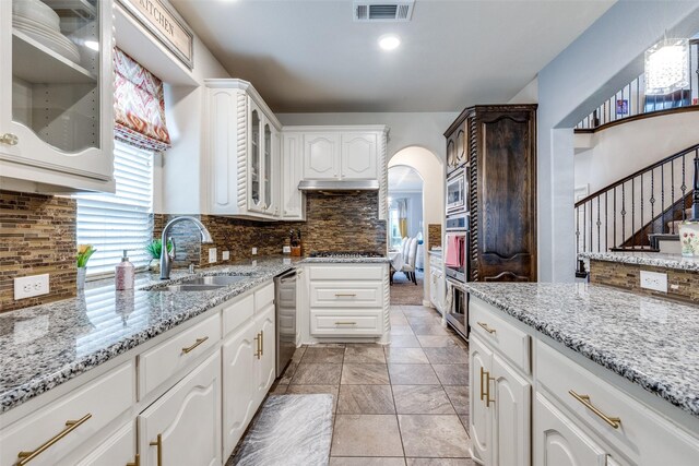 1332 Needle Cactus Dr, Fort Worth, TX 76177 - kitchen featuring a sink, stainless steel appliances, backsplash, glass insert cabinets, and light stone counters