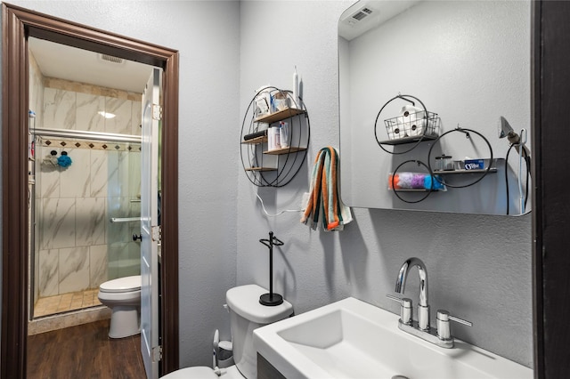 741 N Robinson St, Cleburne, TX 76031 - bathroom with toilet, a sink, a shower stall, wood finished floors, and a textured wall