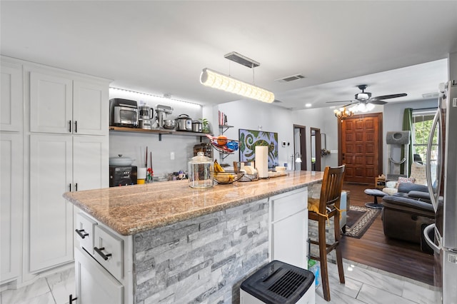 741 N Robinson St, Cleburne, TX 76031 - kitchen with white cabinetry, light stone counters, light marble finish floors, and ceiling fan