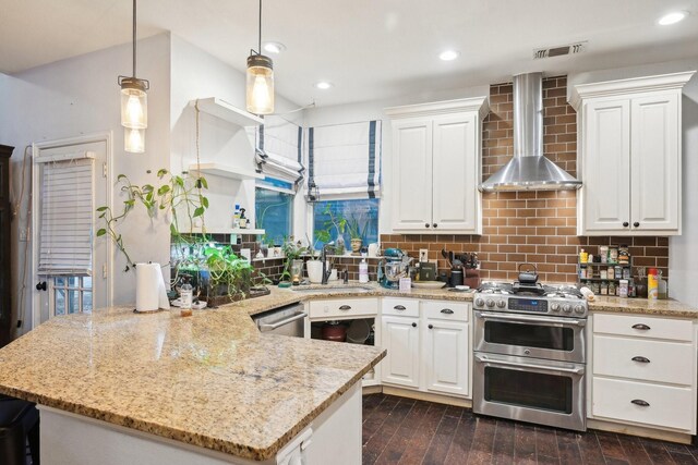 kitchen featuring wall chimney range hood, stainless steel appliances, white cabinetry, tasteful backsplash, and a peninsula