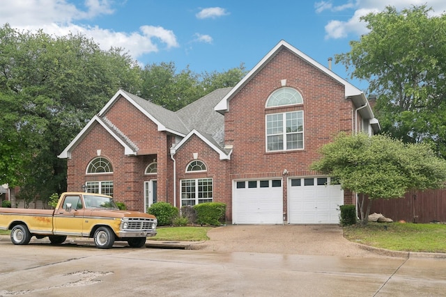 traditional home with concrete driveway, brick siding, a garage, and fence