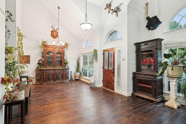 foyer entrance with high vaulted ceiling, hardwood / wood-style floors, baseboards, and a chandelier