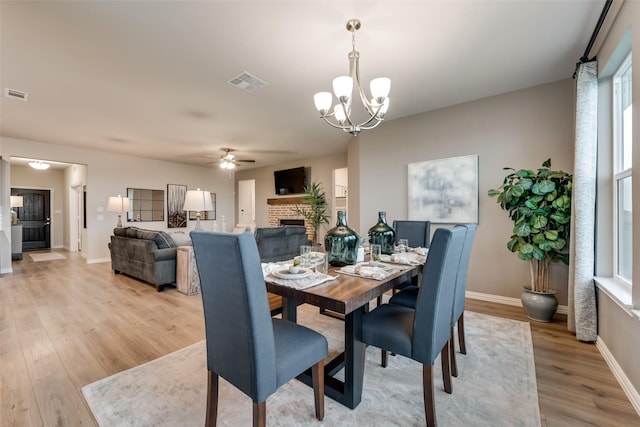 126 Range Ln, Decatur, TX 76234 - dining room with a ceiling fan, a brick fireplace, light wood finished floors, a chandelier, and baseboards
