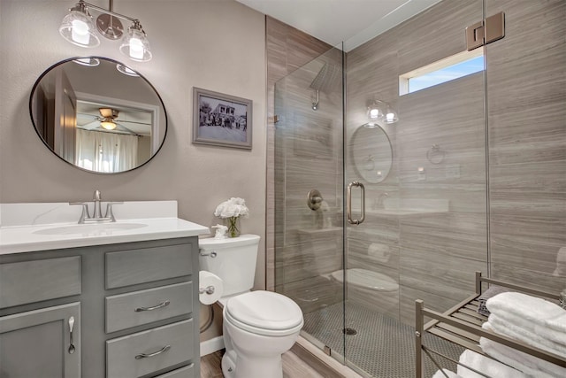 bathroom featuring toilet, a stall shower, vanity, and ceiling fan