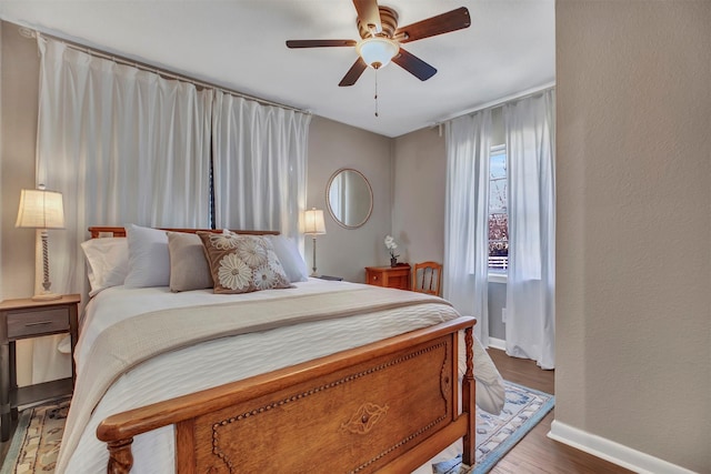 bedroom featuring wood finished floors, baseboards, a ceiling fan, and a textured wall
