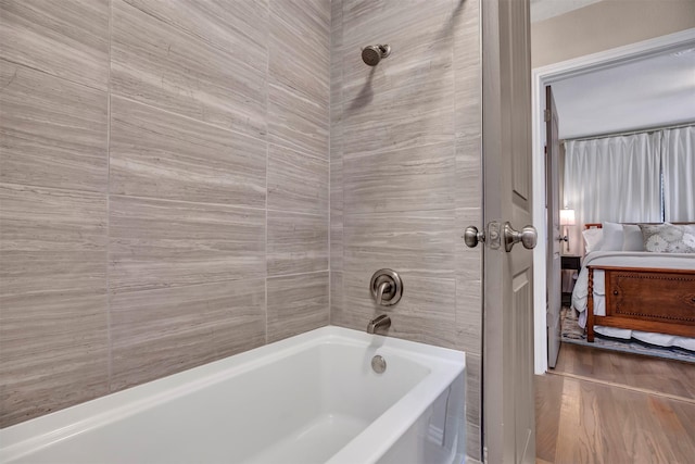 ensuite bathroom featuring shower / tub combination and wood finished floors
