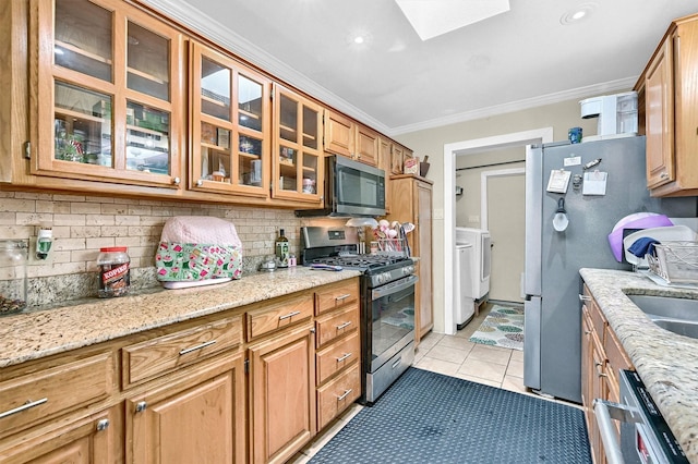 112 S Wood Ave, Denison, TX 75020 - kitchen featuring appliances with stainless steel finishes, a skylight, tasteful backsplash, washer and clothes dryer, and ornamental molding