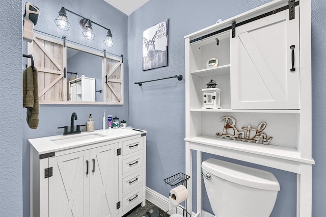 112 S Wood Ave, Denison, TX 75020 - bathroom featuring vanity, toilet, a textured wall, and baseboards