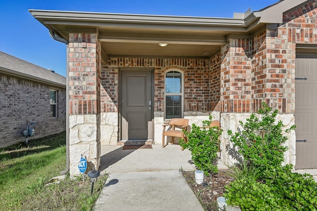 view of exterior entry with brick siding and an attached garage