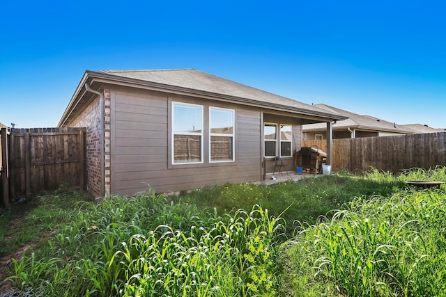 rear view of property with a fenced backyard and a patio