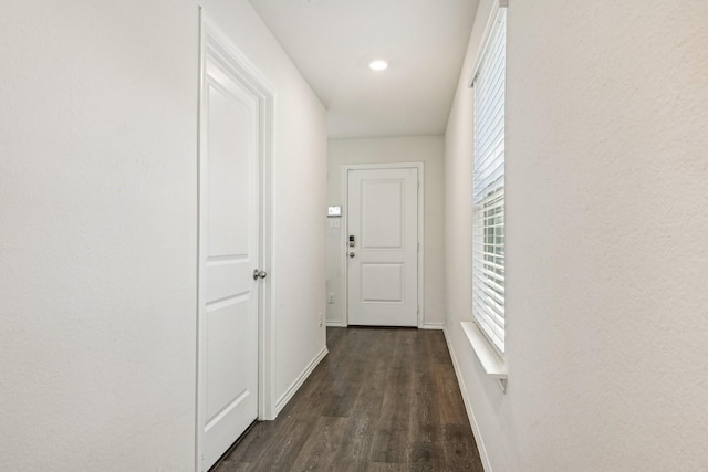 corridor featuring dark wood-style flooring, baseboards, and healthy amount of natural light