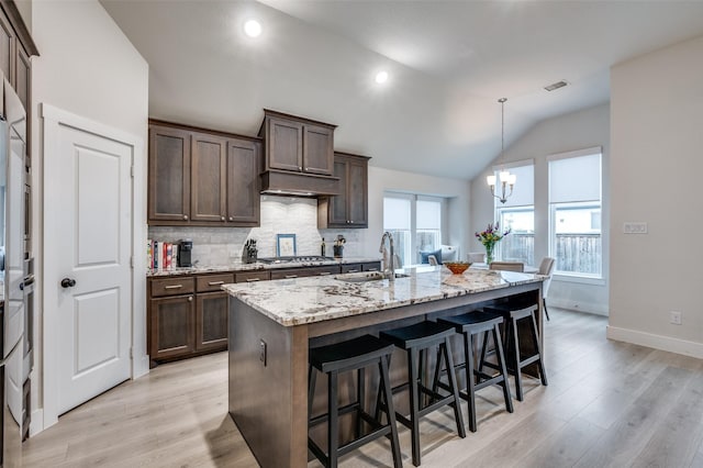 7412 Foxgrass Pl, Fort Worth, TX 76123 - kitchen with a sink, lofted ceiling, light wood-type flooring, a breakfast bar, and light stone countertops