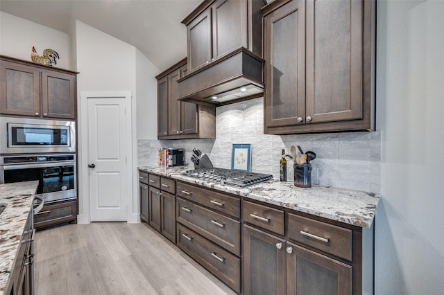 7412 Foxgrass Pl, Fort Worth, TX 76123 - kitchen featuring appliances with stainless steel finishes, dark brown cabinetry, tasteful backsplash, vaulted ceiling, and light wood finished floors