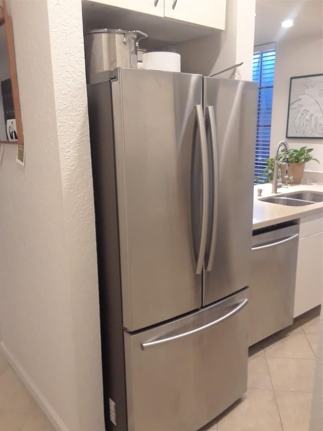 3817 Gilbert Ave Unit 108, Dallas, TX 75219 - kitchen with appliances with stainless steel finishes, light tile patterned floors, a sink, white cabinetry, and light countertops