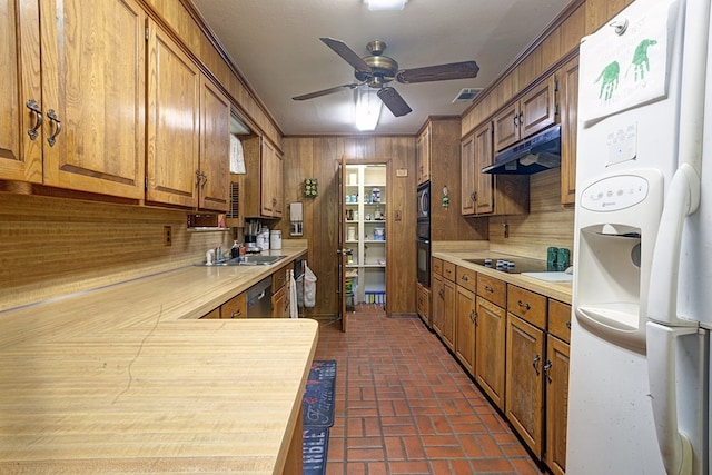 kitchen with brick floors, appliances with stainless steel finishes, wooden walls, a ceiling fan, and under cabinet range hood