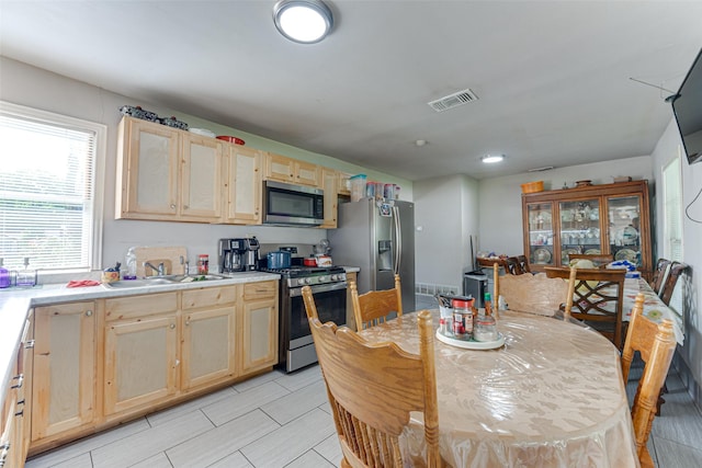 2957 Darby Dr, Dallas, TX 75227 - kitchen with appliances with stainless steel finishes, light brown cabinetry, a sink, and light countertops