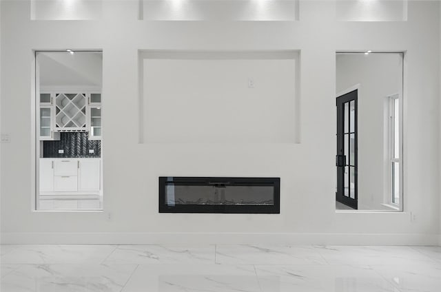 detailed view of a glass covered fireplace, baseboards, and tasteful backsplash